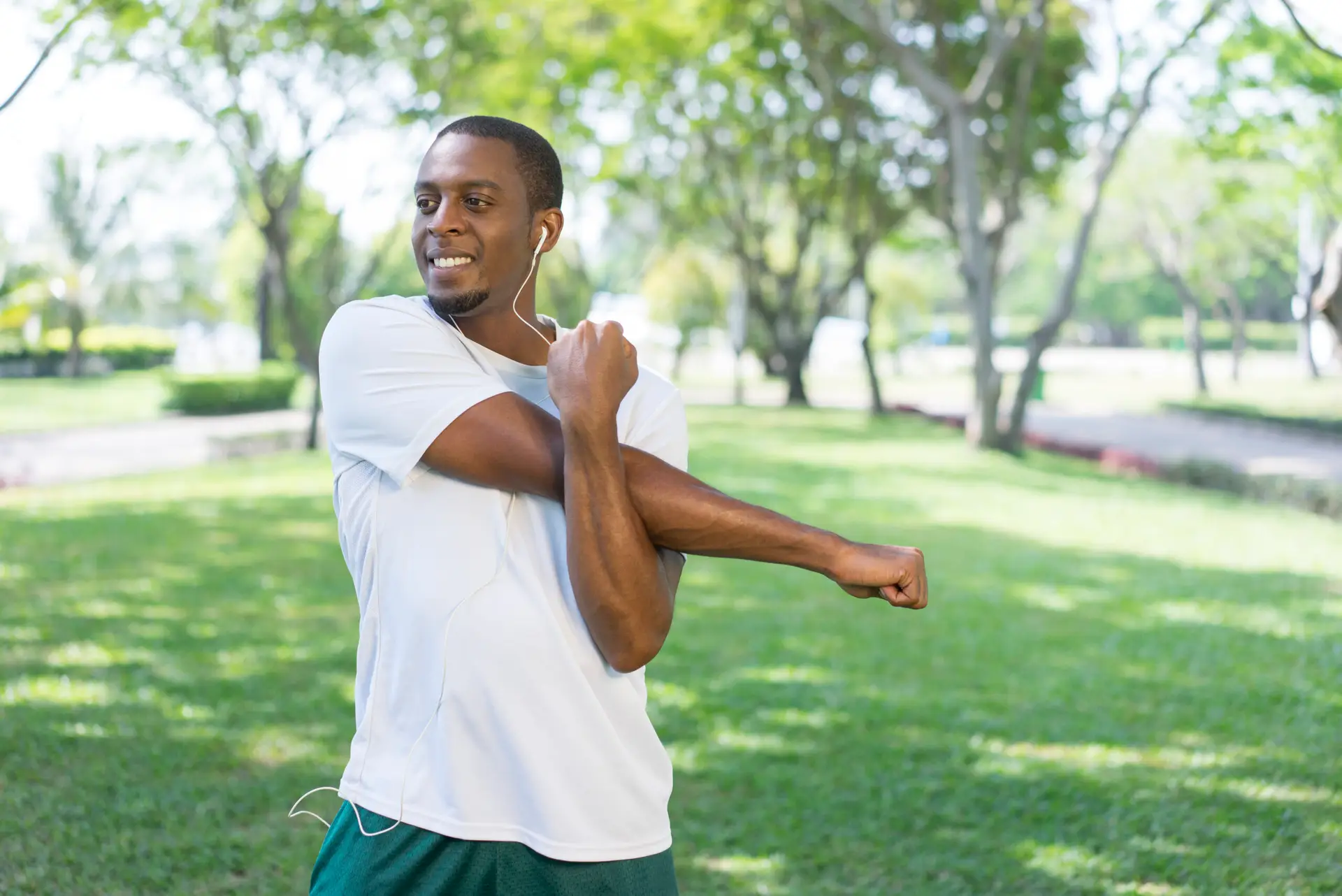 smiling-sporty-black-man-listening-music-doing-morning-exercises-park